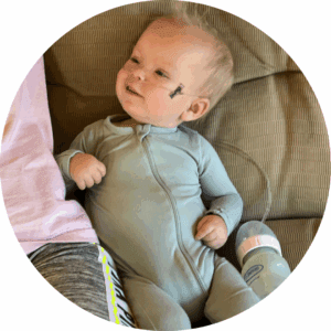 Daxton wears green pajamas and looks up at his family.