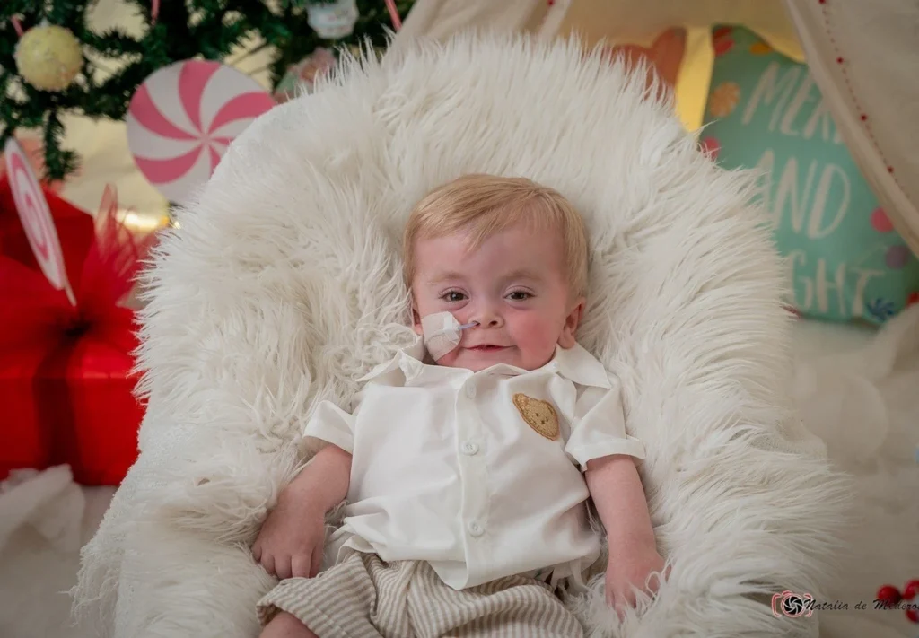 Milo dressed in white for Christmas, resting on a soft white blanket