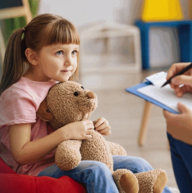 Young girl holding a teddy bear during a doctor visit